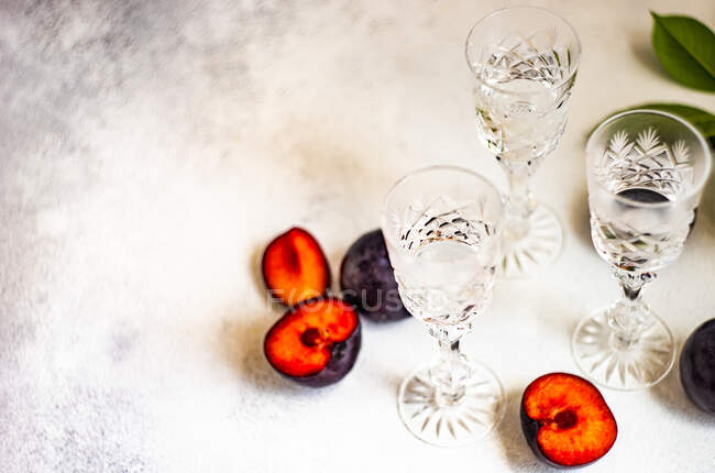 Plum vodka served in cold glasses and fresh plums on a table — Stock Photo