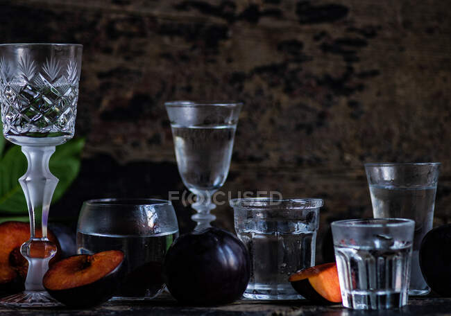 Плюмова горілка подається в холодних склянках і свіжих сливах на столі. — стокове фото