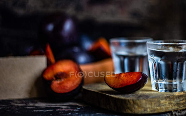 Plum vodka served in cold glasses and fresh plums on a table — Stock Photo
