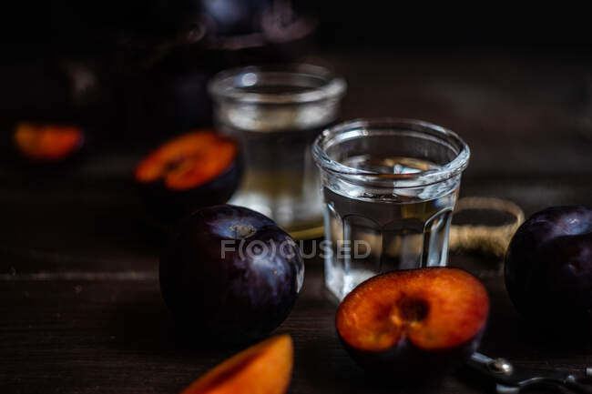 Сливовая водка в холодных стаканах и свежие сливы на столе — стоковое фото