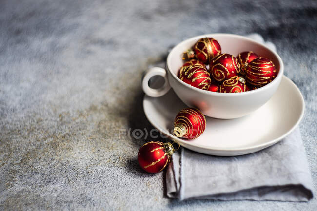 Концепція різдвяної листівки з білою чашею, повна червоних різдвяних кульок — стокове фото