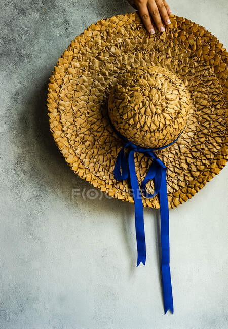 Mano di donna tenendo un cappello di paglia contro il muro — Foto stock