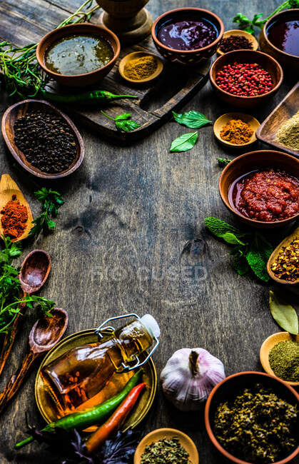 Вид сверху на разнообразные травы, специи, соусы и приправы на столе — стоковое фото