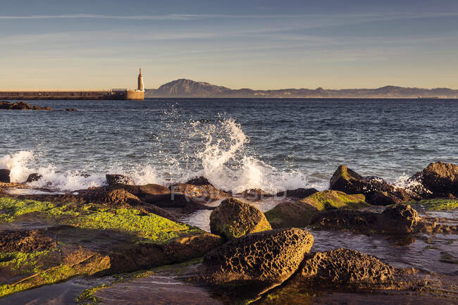 Хвилі розбиваються на пляжі Playa Chica з статуєю Святого Серця Ісуса і Пунта-дель-Санто на відстані, Таріфа, Кадіс, Андалусія, Іспанія — стокове фото