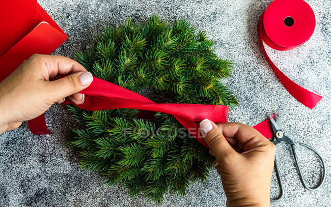 Overhead view of a woman tying a ribbon on a fir wreath — Stock Photo