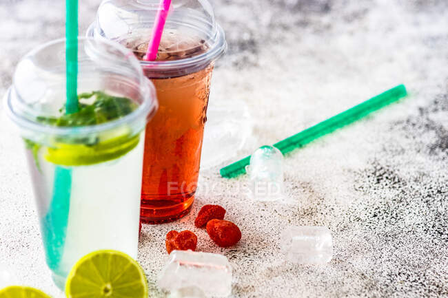 Limonada de morango e limão com limonada de hortelã em uma mesa com cubos de gelo, limão fresco e morangos — Fotografia de Stock