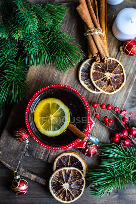 Cup of tea with lemon next to a wrapped christmas gift, decorations and ornaments — Stock Photo