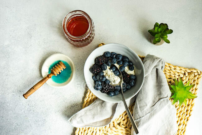 Overhead view of a bowl of blueberries and blackberries with cottage cheese and honey — Stock Photo