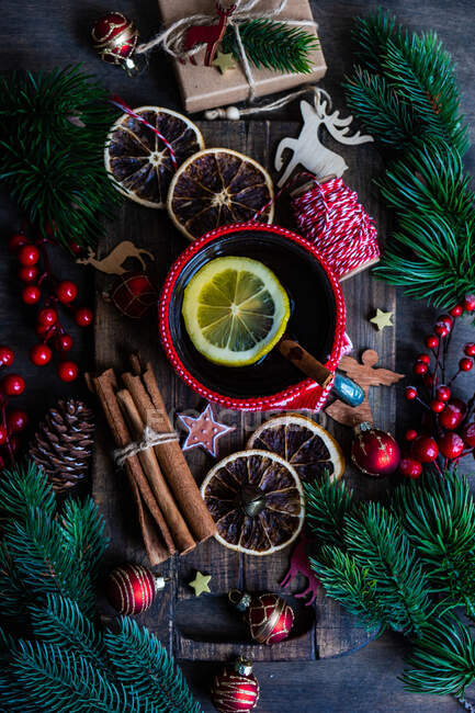 Чашка чаю з лимоном поруч із загорнутим різдвяним подарунком, прикрасами та прикрасами — стокове фото