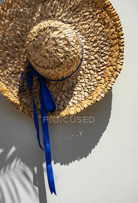 Вигляд літнього солом'яного капелюха з синьою стрічкою на столі. — стокове фото