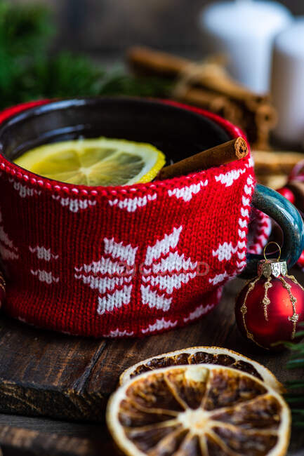 Tasse Tee mit Zitrone neben einem verpackten Weihnachtsgeschenk, Dekorationen und Ornamenten — Stockfoto