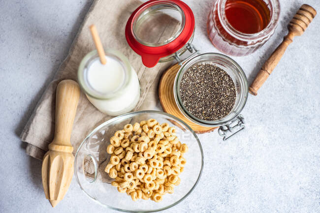 Bowl of cereal next to a bottle of milk, chia seeds and honey — Stock Photo