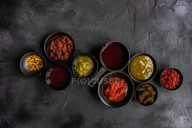 Vista aérea de una variedad de hierbas, especias, salsas y condimentos sobre una mesa - foto de stock