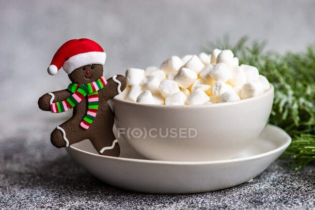 Різдвяний імбирний чоловік у печиві з капелюхом Санта поруч з чашкою міні зефіру — стокове фото
