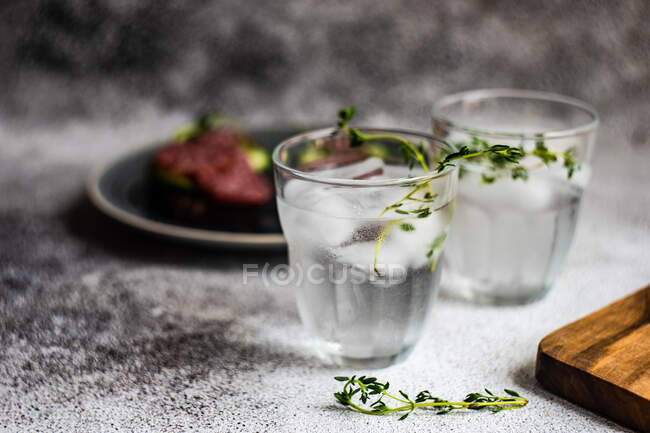Two glasses of water with cucumber and salami open sandwiches — Stock Photo