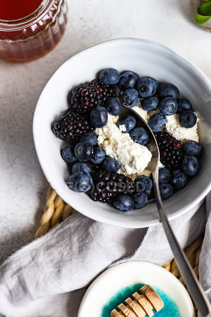 Overhead view of a bowl of blueberries and blackberries with cottage cheese and honey — Stock Photo