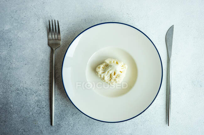 Overhead view of a raw cauliflower floret on a plate — Stock Photo