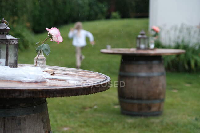 Rear view of a girl in a garden running out of the rain towards a house, France — Stock Photo