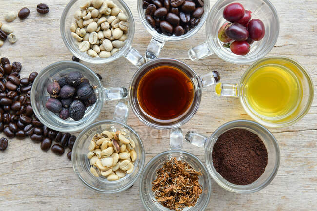Overhead view of assorted cups with coffee, coffee berries and coffee beans — Stock Photo