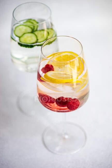 Two glasses of ice water with cucumber and raspberries with lemon — Stock Photo