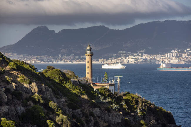 Faro de Punta Carnero con Roca de Gibraltar en la distancia, Cádiz, Andalucía, España - foto de stock