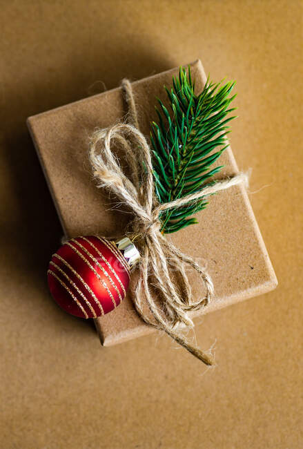 Caja de regalo rústica decorada con una rama de pino y adorno de Navidad - foto de stock