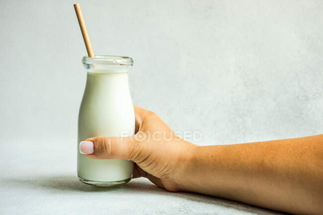 Donna con in mano una bottiglia vintage di latte con una cannuccia da bere — Foto stock