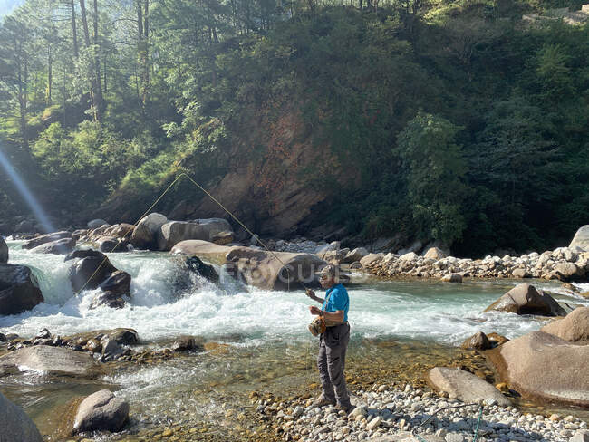 Pesca della trota dell'uomo in un fiume nell'Himalaya, India — Foto stock