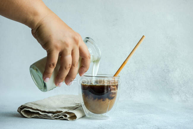 Mulher derramando leite em uma xícara de café — Fotografia de Stock