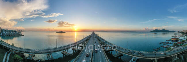 Coches conduciendo a través del puente de Penang al amanecer, Penang, Malasia - foto de stock