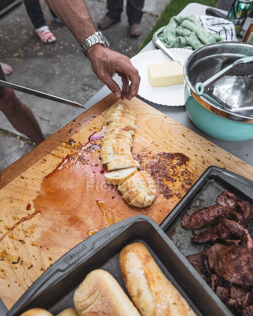 Close-up of a man slicing bread on a chopping board at a barbecue, USA — Stock Photo