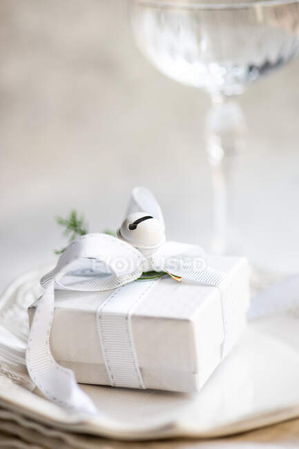 Wrapped christmas gift on a napkin next to a champagne coupe on a table — Stock Photo