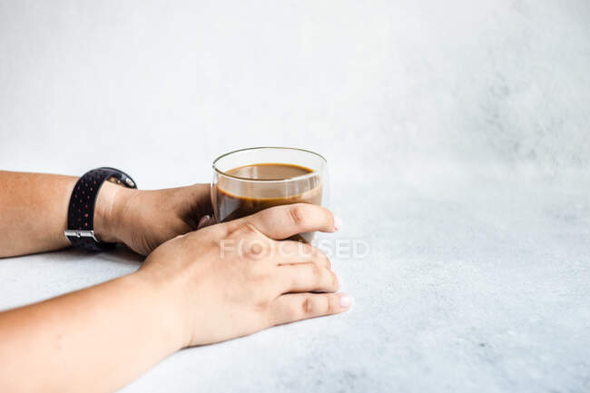 Mujer sentada en una mesa con una taza de café - foto de stock