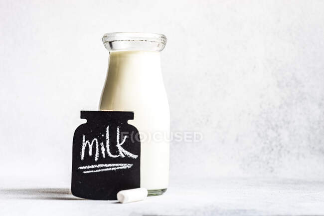 Слово молоко на крейдяній дошці поруч з старовинною пляшкою молока — стокове фото