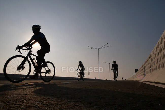 Silhouette von drei Radfahrern auf der Straße bei Sonnenaufgang, Indonesien — Stockfoto