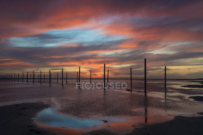 Postos de madeira na praia ao pôr do sol, Los Lances praia, Tarifa, Cádiz, Andaluzia, Espanha — Fotografia de Stock