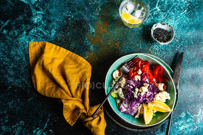 Cena sana con ciotola biologica servita su un tavolo con semi di sesamo e bicchiere di acqua al limone — Foto stock