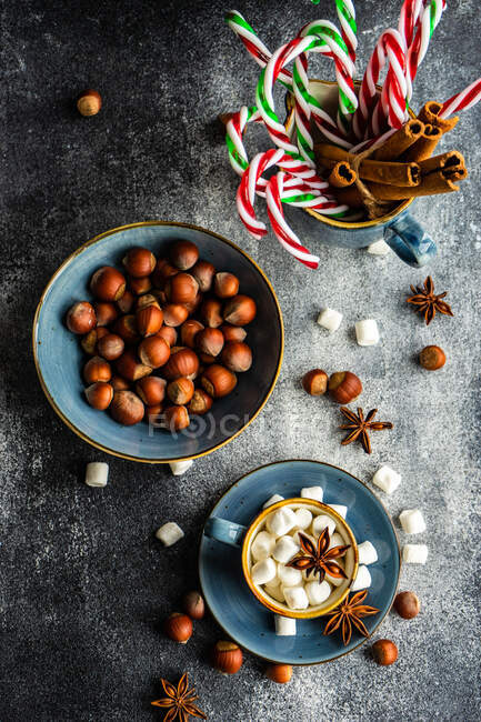 Tasses pleines de mini guimauves avec des épices sur fond sombre comme concept de nourriture de Noël — Photo de stock