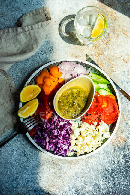 Gesundes Abendessen mit Bio-Gemüseschale auf einem Tisch mit Sesam und einem Glas Zitronenwasser — Stockfoto