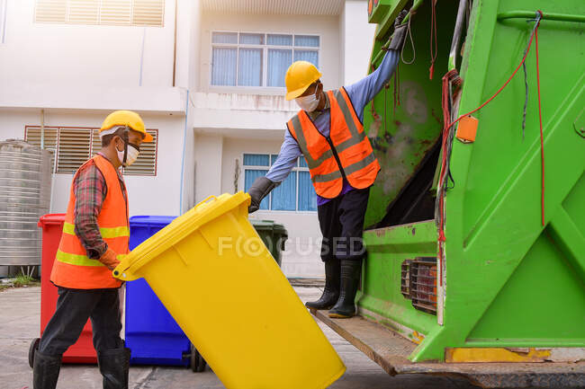 Caminhão de lixo reciclável e o detentor na aldeia.Coletor de lixo no caminhão de lixo. varredor ou trabalhador estão carregando resíduos no transportador de caminhão de lixo. — Fotografia de Stock