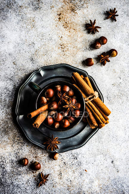 Concepto de comida navideña con copa vintage llena de nueces, palitos de canela y estrella de anís sobre fondo de hormigón - foto de stock