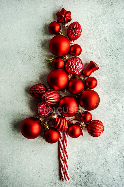 Концепция рождественской открытки с рождественской елкой в форме красных декоративных шариков и конфет — стоковое фото