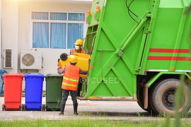 Caminhão de lixo reciclável e o detentor na aldeia.Trabalhador estão carregando resíduos no transportador de caminhão de lixo. — Fotografia de Stock