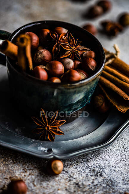 Concepto de comida navideña con copa vintage llena de nueces, palitos de canela y estrella de anís sobre fondo de hormigón - foto de stock
