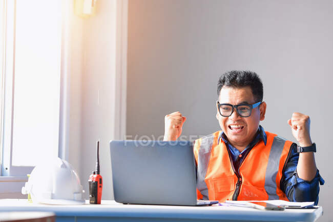 Ingeniero de construcción civil que trabaja con computadora portátil en la oficina de escritorio en el sitio de construcción. - foto de stock