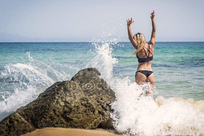 Giovane donna con i capelli lunghi seduta sulla spiaggia soleggiata — Foto stock