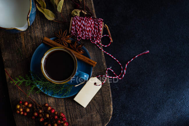 Різдвяна пряна кава в синьому керамічному кубку серед спецій та ягід на темному фоні — стокове фото