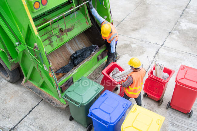 Caminhão de lixo reciclável e o detentor na aldeia.varredor ou trabalhador estão carregando resíduos no transportador de caminhão de lixo. — Fotografia de Stock