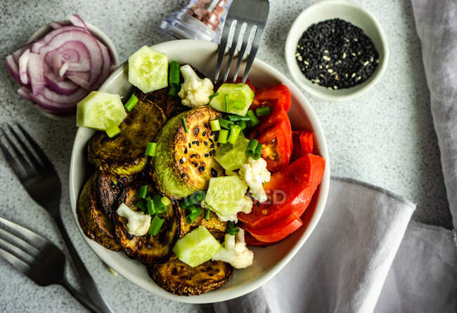 Tazón de verduras saludable con pepino, tomate, cebolla verde y col con semillas de sésamo - foto de stock