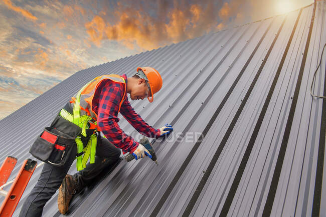 Toiture Travailleur de la construction installer un nouveau toit. Outils de toiture. Perceuse électrique utilisée sur les nouveaux toits avec tôle. — Photo de stock